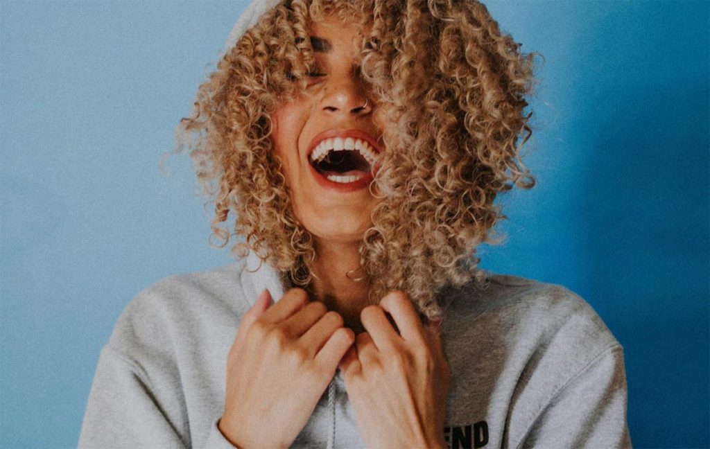 photo of a happy african american woman in blue wall background wearing hoodie