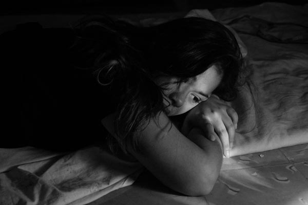 photo of a woman lying in bed suffering from anxiety
