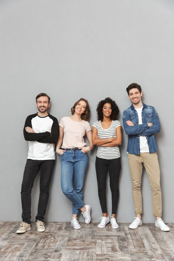 Image of happy group of friends standing over a grey wall