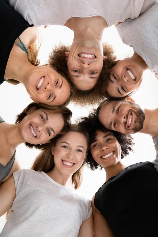 low angle group of diverse people smiling standing in a circle