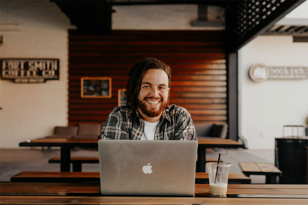 photo of a happy man in front of a laptop smiling for the camera