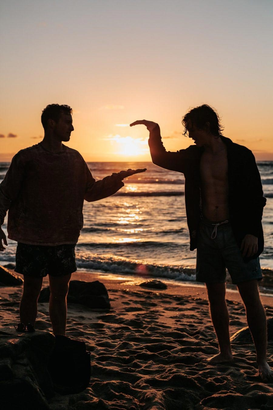 photo of close-up photo of two men shaking hands near beach at sunset