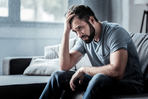 photo of handsome man sitting on a sofa sad, lonely and depressed