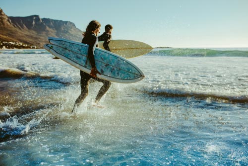 photo of two male surfers going for surfing in the sea