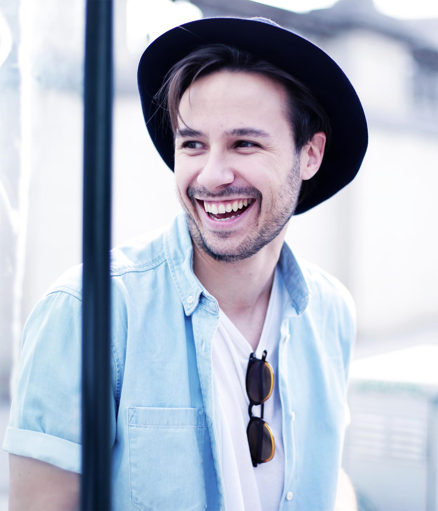 a happy young man wearing white shirt and light blue denim polo