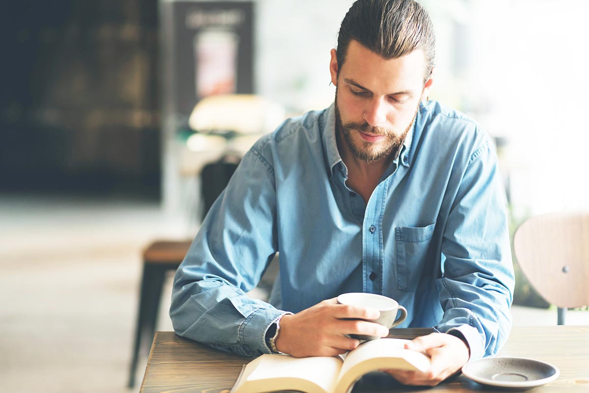 man drinking coffee while reading a book as brain exercise