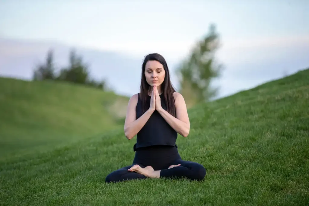 woman meditating outdoor sitting on the grass