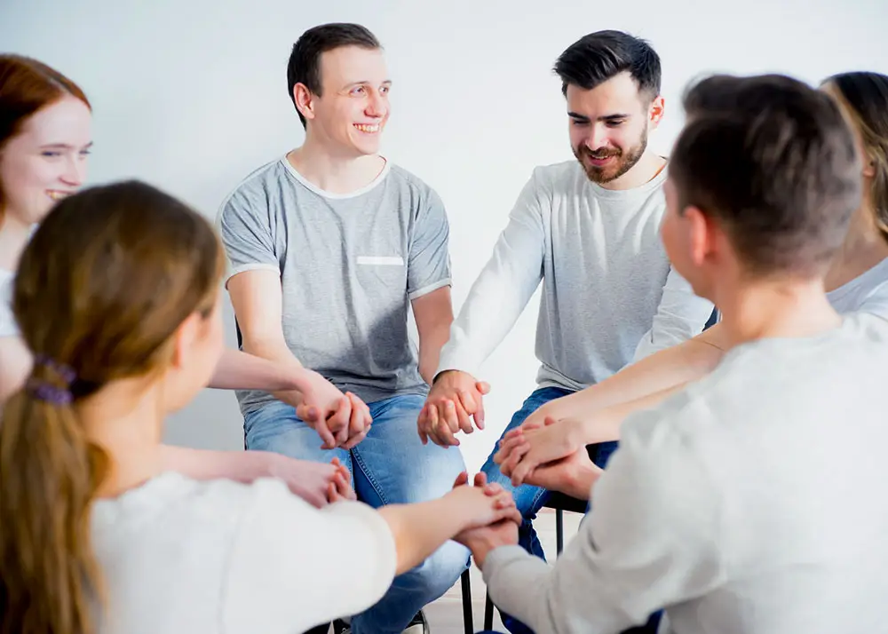 men and women during group therapy holding hands supporting each other at a mental health treatment center in los angeles california