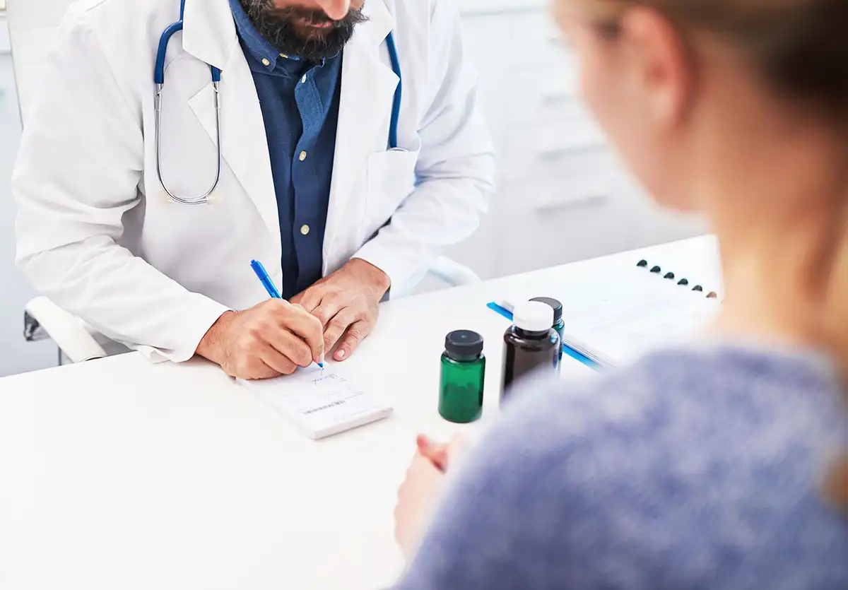 A doctor writes on a clipboard as a woman observes, highlighting the importance of communication in addressing prescription drug addiction