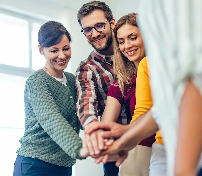 Smiling people from the group therapy, holding hands together, one over the other