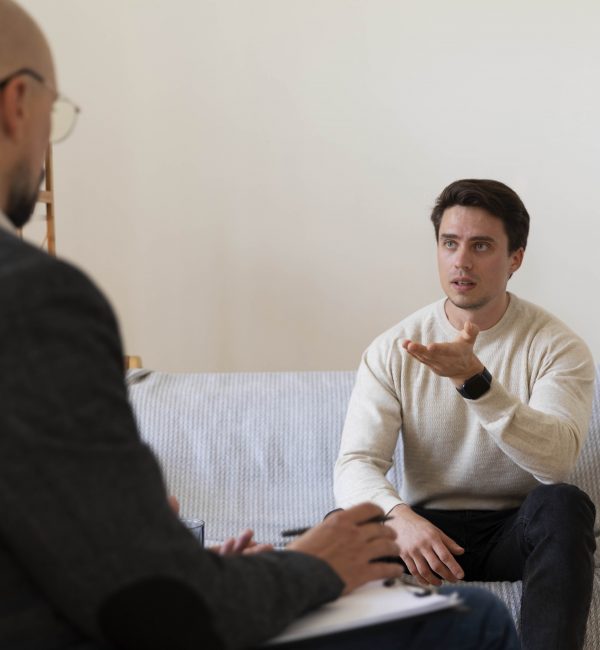 Adult male patient speaking with a therapist during a professional ADHD counseling session in a calm office setting
